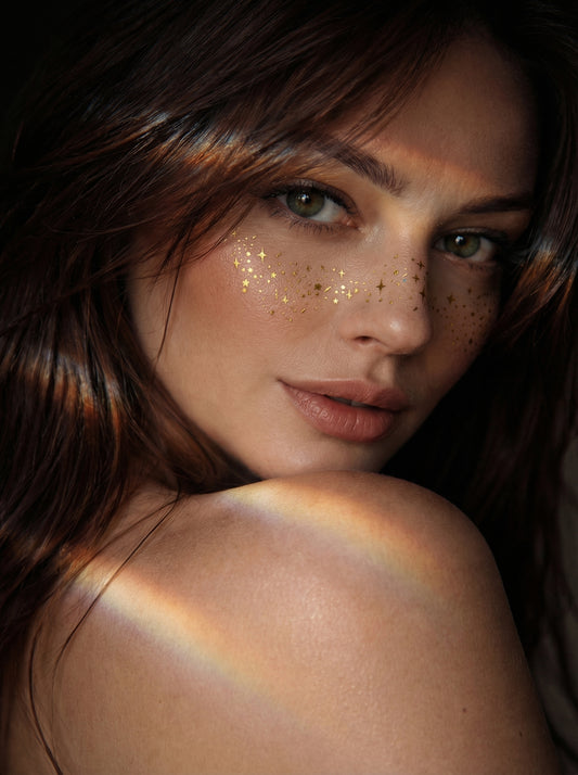 Woman with glitter on her face and a rainbow on her shoulder